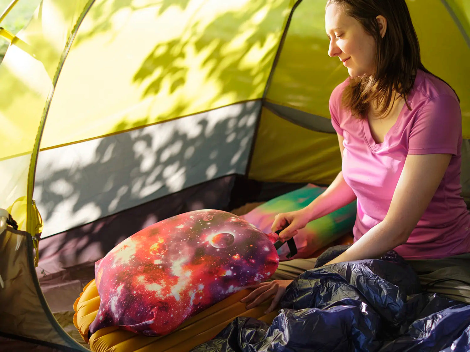 Woman attaching Pillow Strap to camp sleeping pad to hold camp pillow in place while camping